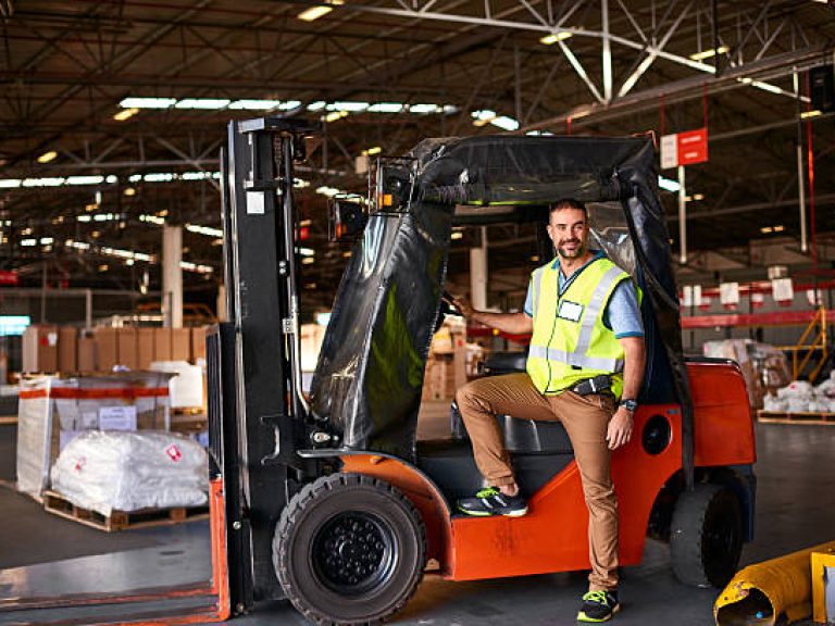 Portrait of smiling forklift operator in a large warehouse